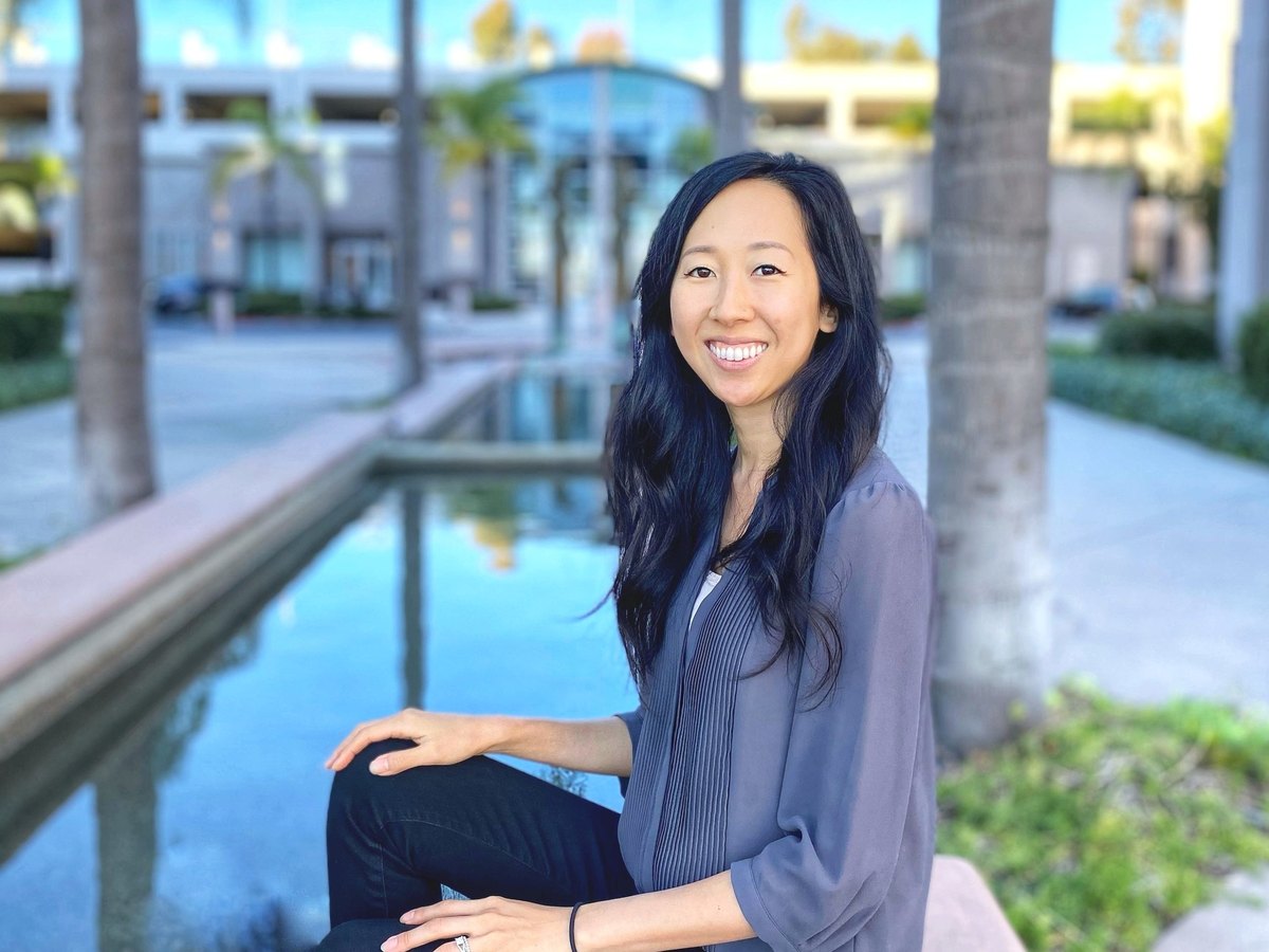 Vicky, integrative health pharmacist, seated outdoors by a reflecting pool